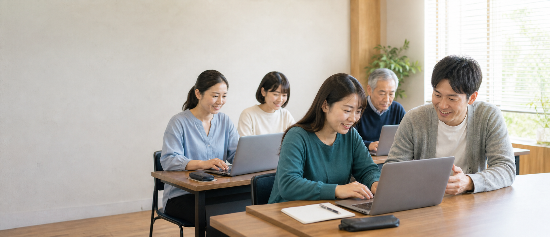 若い男性講師と幅広い世代・多様な背景の5人の受講者が笑顔でAI・Java・Pythonを学ぶ様子